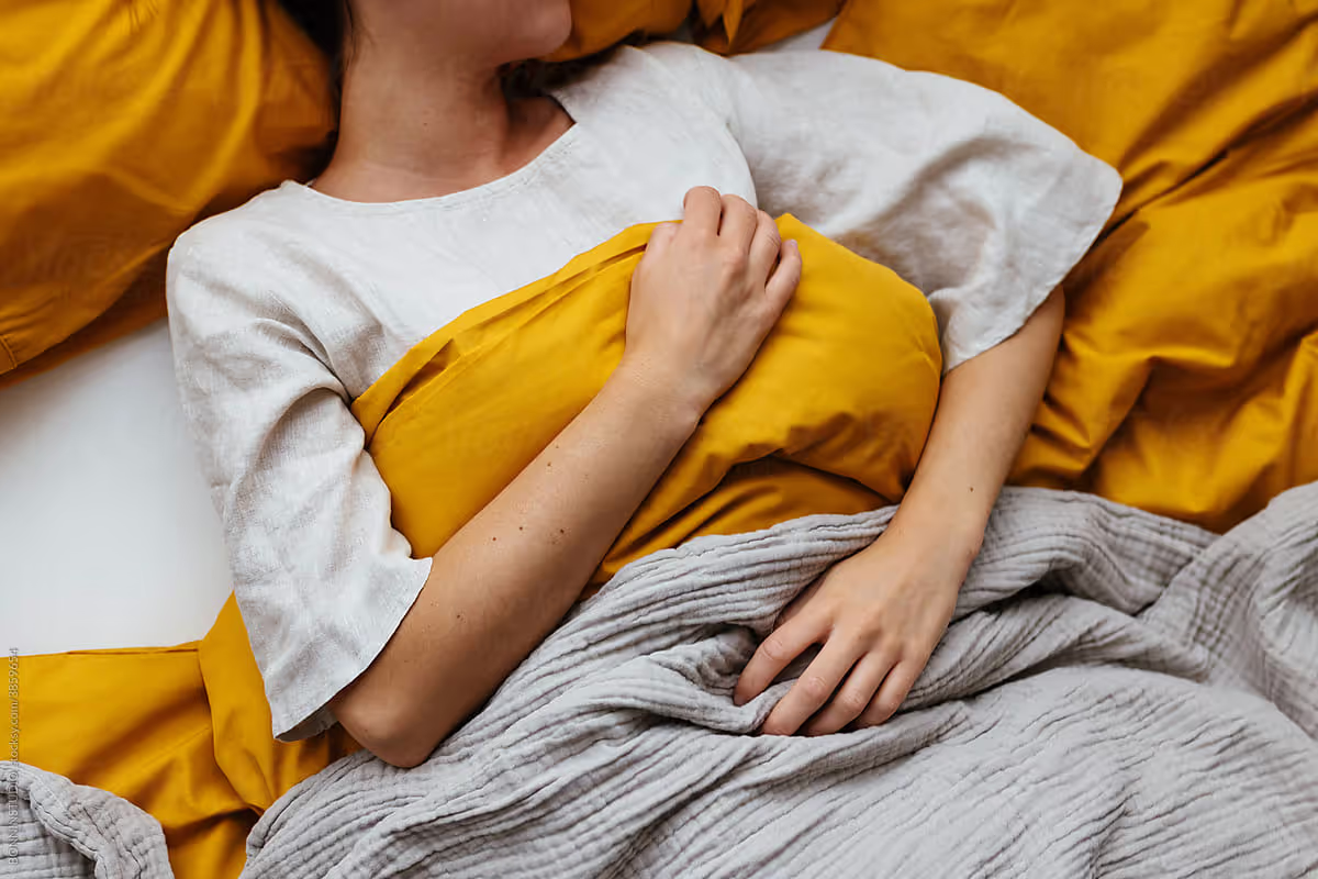 Woman lying in bed with yellow covers.