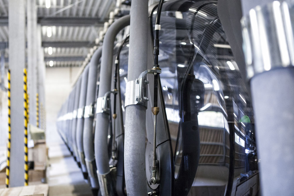 Detailansicht nebeneinander gelagerter Sessel mit Tragseilen und Wetterschutzhauben in einer technischen Halle