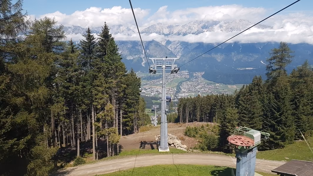 Aussicht aus der Glungezerbahn durch Wald und Tal bis zu den Alpen