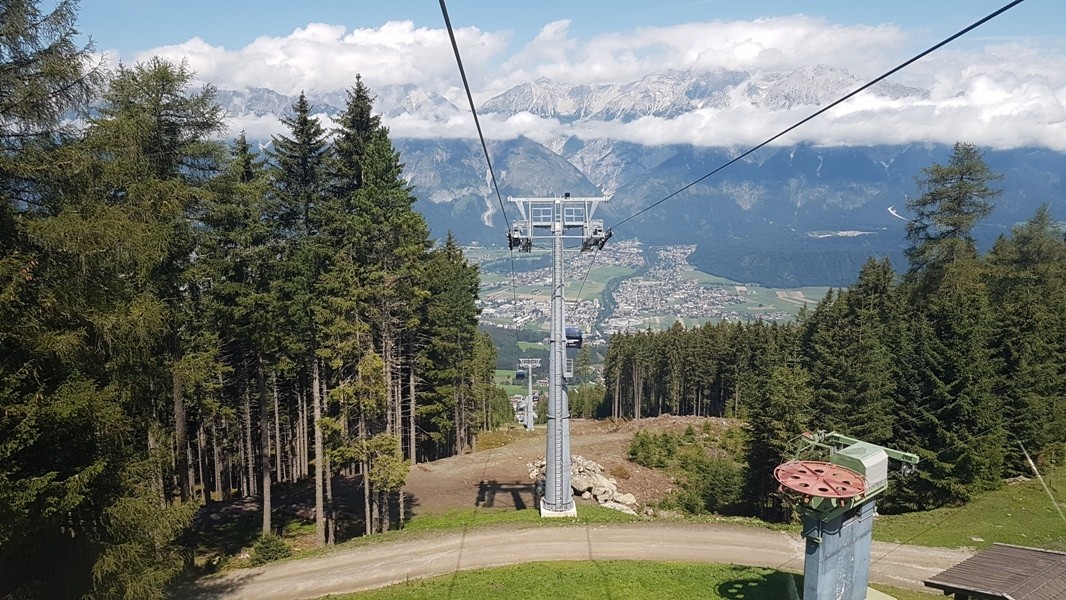 Aussicht aus der Glungezerbahn durch Wald und Tal bis zu den Alpen