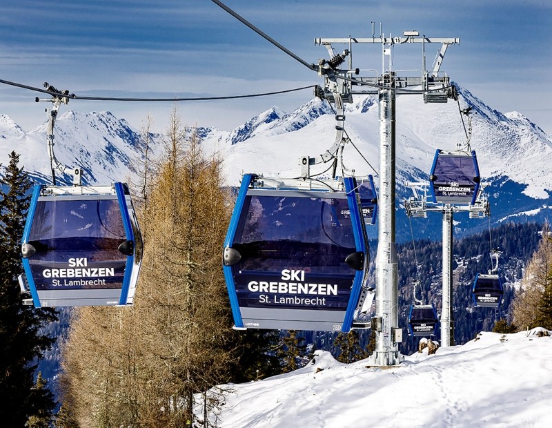 Blaue Gondeln der Ski Grebenzen Bahn in St. Lambrecht vor winterlicher Bergkulisse