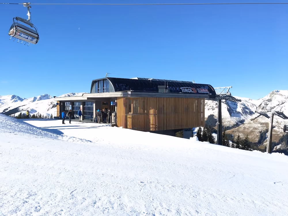TirolS-Bergstation mit Wintersportlern vor blauem Himmel
