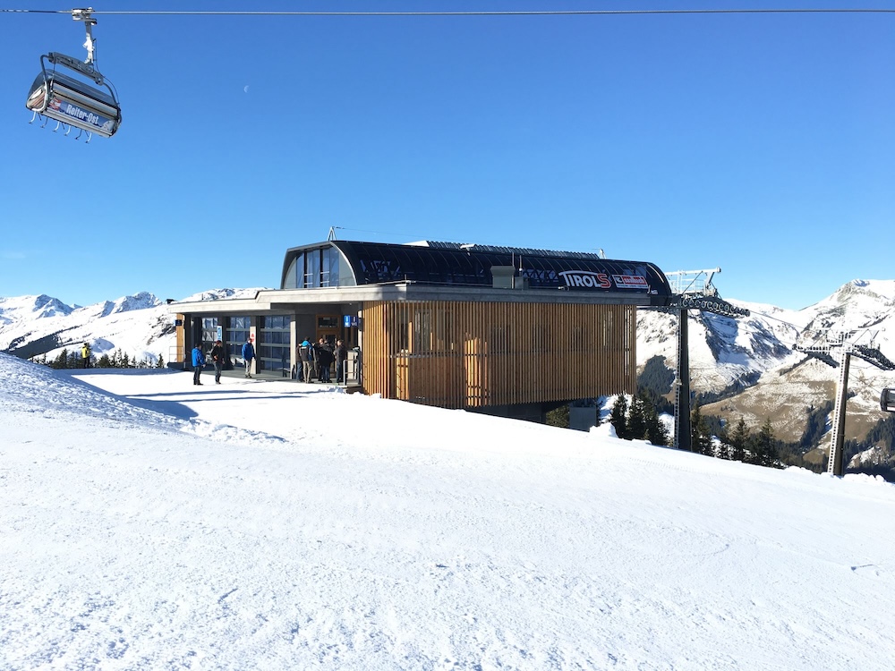 TirolS-Bergstation mit Wintersportlern vor blauem Himmel
