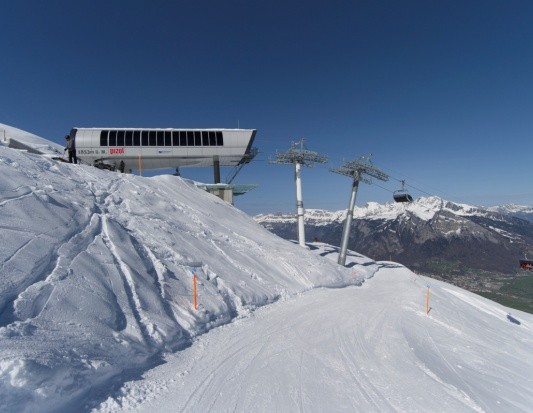 Bergstation mit Gondelbahn und Piste in verschneiter Alpenlandschaft