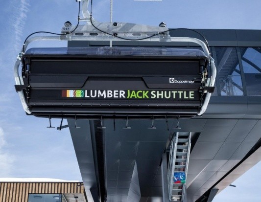 Frontansicht eines modernen 6er-Sessels mit Beschriftung „Lumberjack Shuttle“ an einer Bergstation von Doppelmayr
