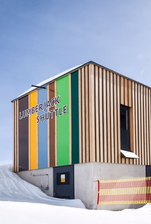 Servicegebäude der Lumberjack Shuttle Bahn mit auffälliger bunter Holzfassade und angrenzender Station im Schnee