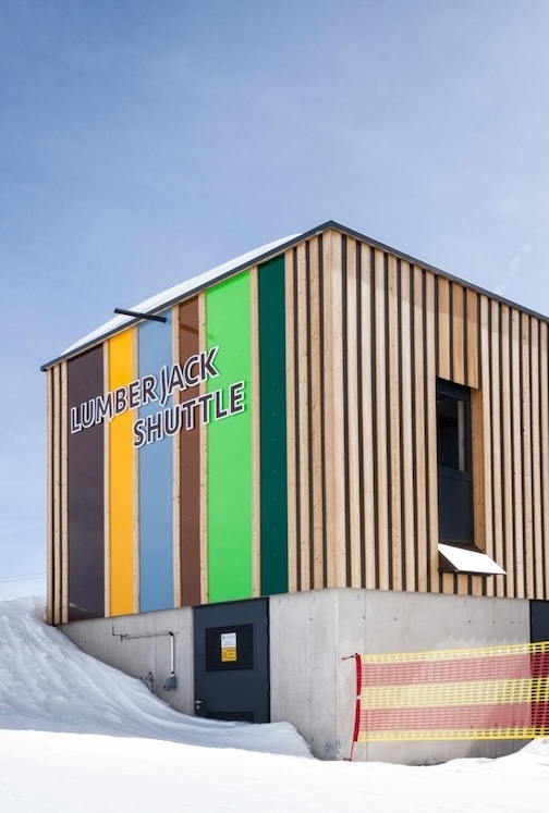 Servicegebäude der Lumberjack Shuttle Bahn mit auffälliger bunter Holzfassade und angrenzender Station im Schnee