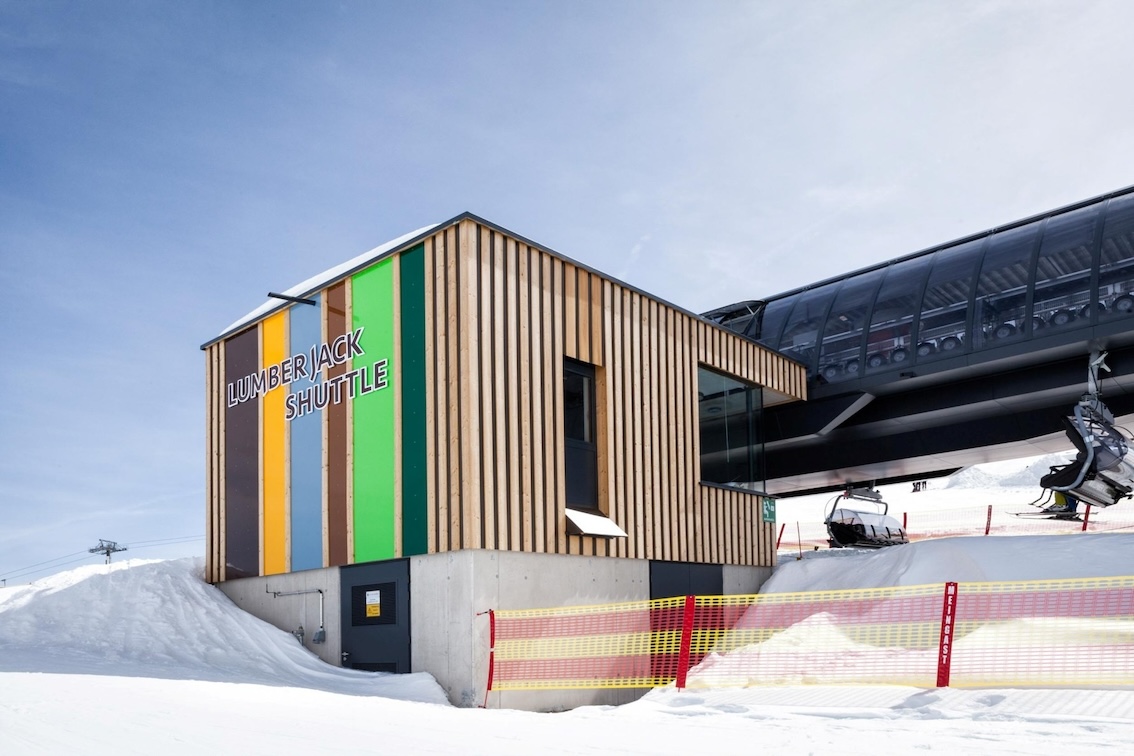 Servicegebäude der Lumberjack Shuttle Bahn mit auffälliger bunter Holzfassade und angrenzender Station im Schnee