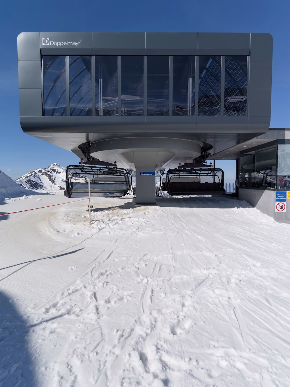 Moderne Bergstation eines Sessellifts im Schnee mit Alpenpanorama