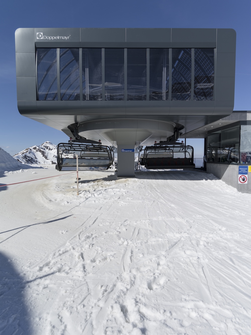 Moderne Bergstation eines Sessellifts im Schnee mit Alpenpanorama