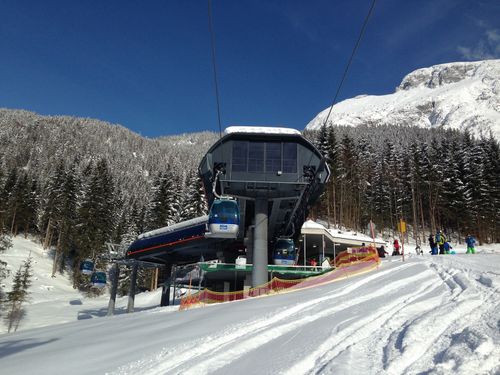 Talstation einer Gondelbahn im verschneiten Skigebiet mit Wald- und Bergkulisse