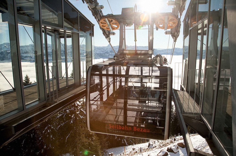 Seilbahnkabine der Seilbahn Bezau fährt in die Bergstation bei Sonnenschein und Schneelandschaft