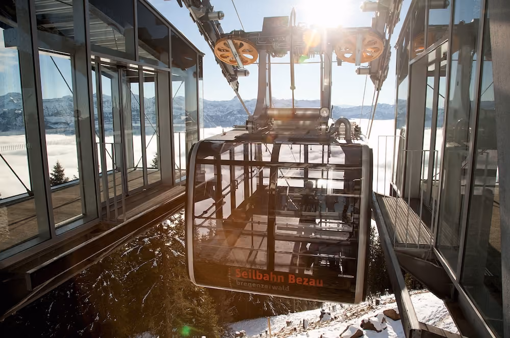 Seilbahnkabine der Seilbahn Bezau fährt in die Bergstation bei Sonnenschein und Schneelandschaft