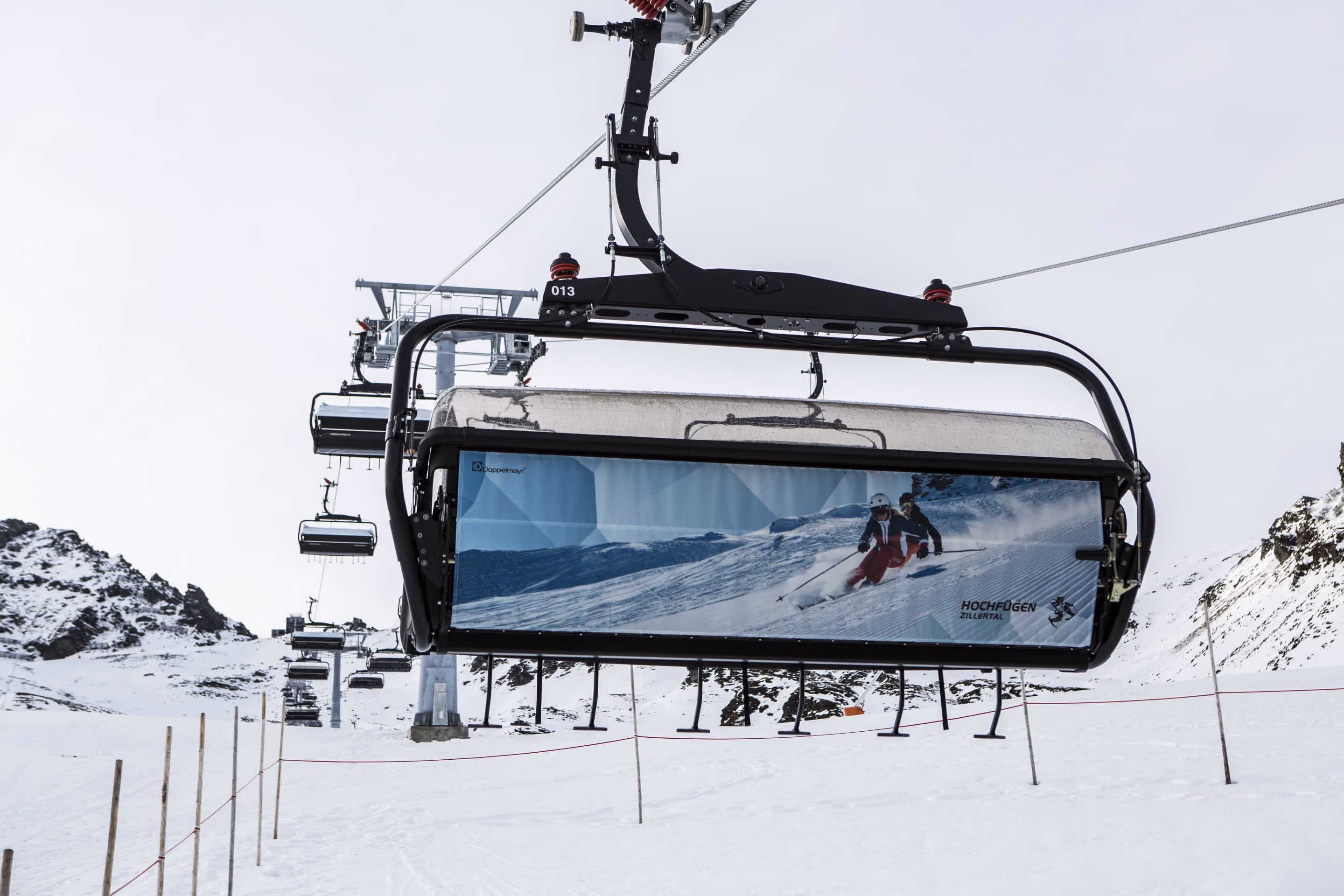Sechsersesselbahn mit Wetterschutzhaube und Werbegrafik im Skigebiet Hochfügen