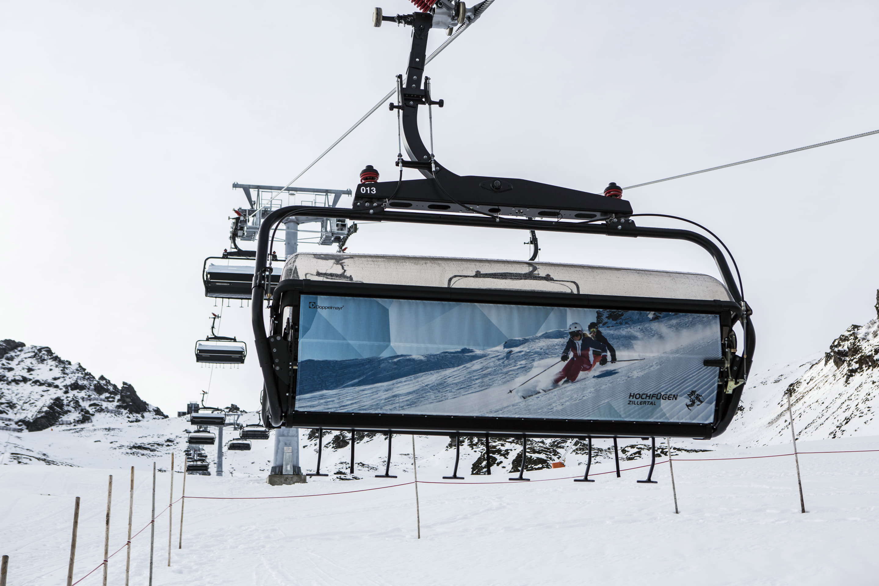 Sechsersesselbahn mit Wetterschutzhaube und Werbegrafik im Skigebiet Hochfügen