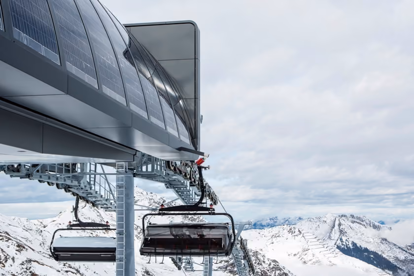 Bergstation mit Solarpaneelen und Sessellift vor verschneiter Landschaft