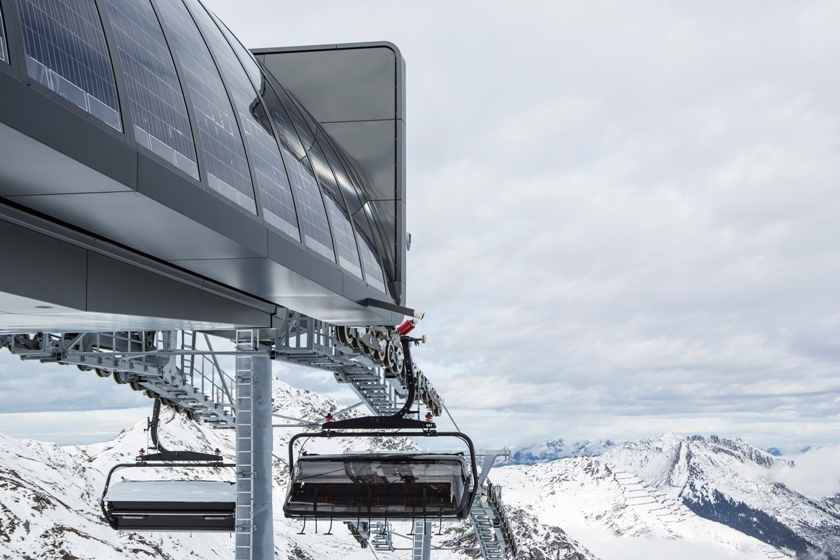 Bergstation mit Solarpaneelen und Sessellift vor verschneiter Landschaft