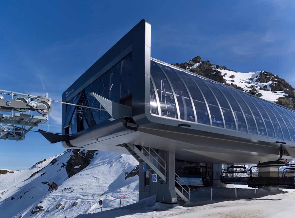 Moderne Seilbahnstation von der Seite mit Glasfassade und verschneitem Hang