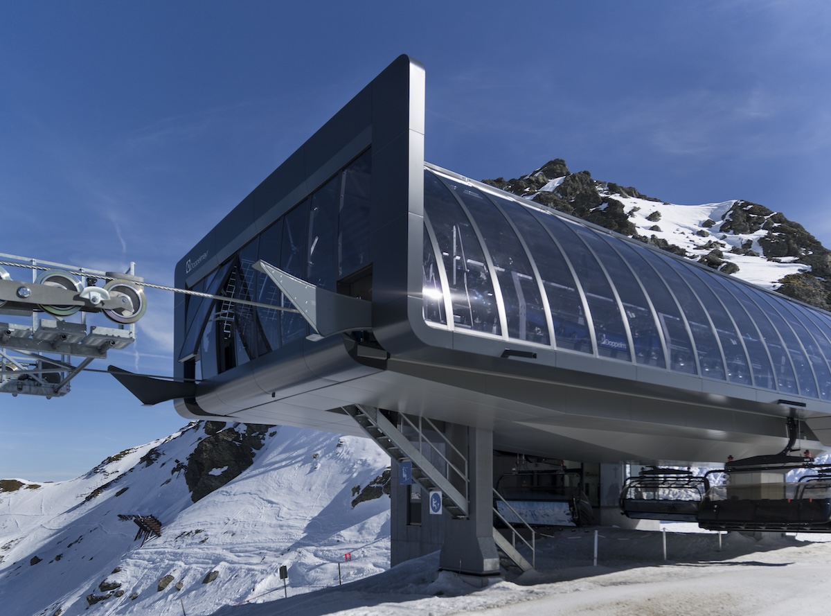 Moderne Seilbahnstation von der Seite mit Glasfassade und verschneitem Hang