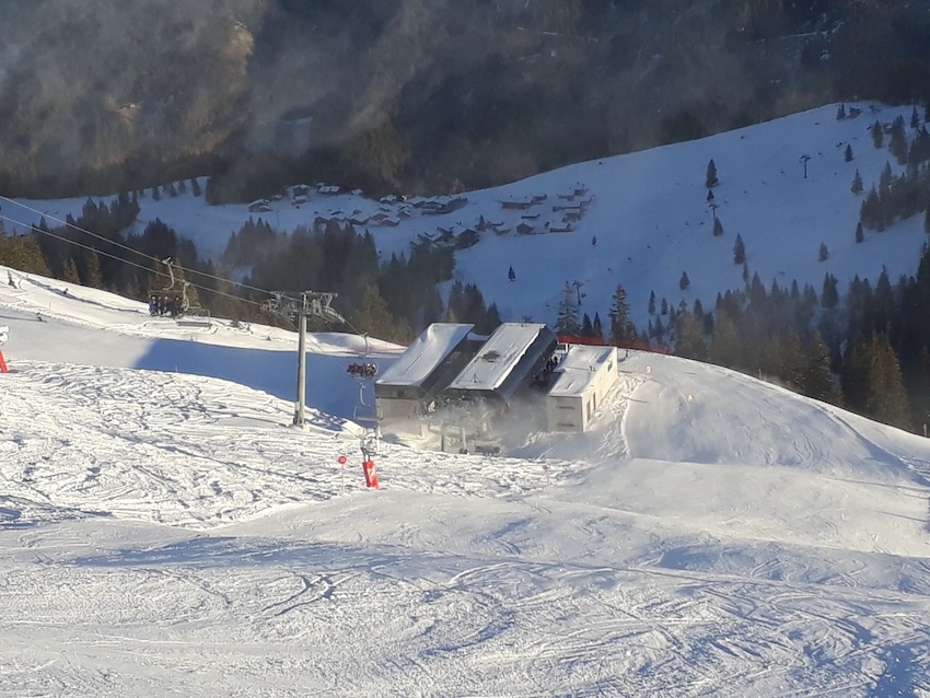 Blick auf eine Talstation mit zwei Sesselbahnspuren und verschneiter Piste im Vordergrund