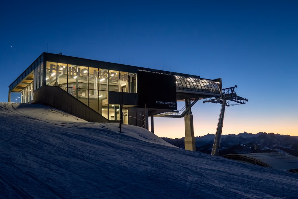 Flying Mozart Bergstation bei Sonnenuntergang mit beleuchtetem Innenraum