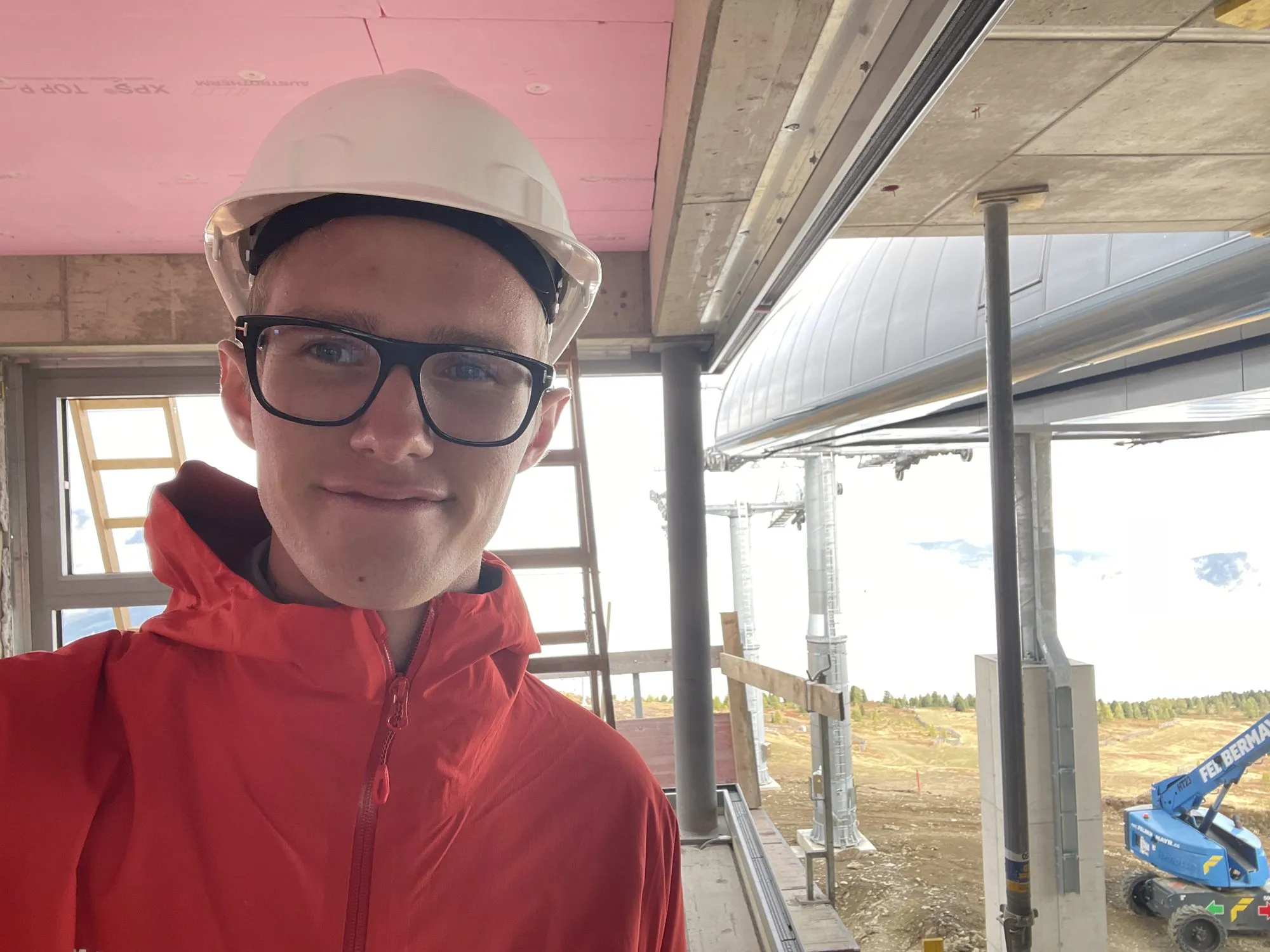 Praktikant Leon Mark mit Bauhelm auf der Seilbahnbaustelle