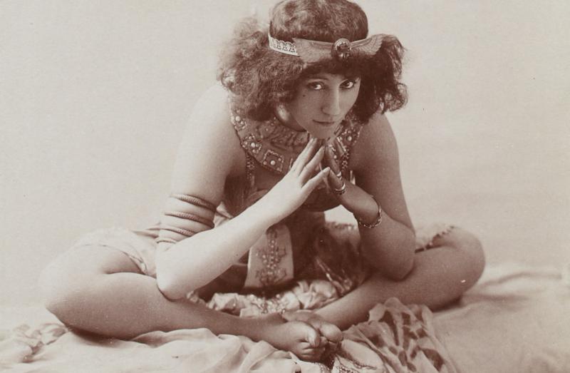 Black and white photo of Natalie Barney lying on her side and on a plush rug.