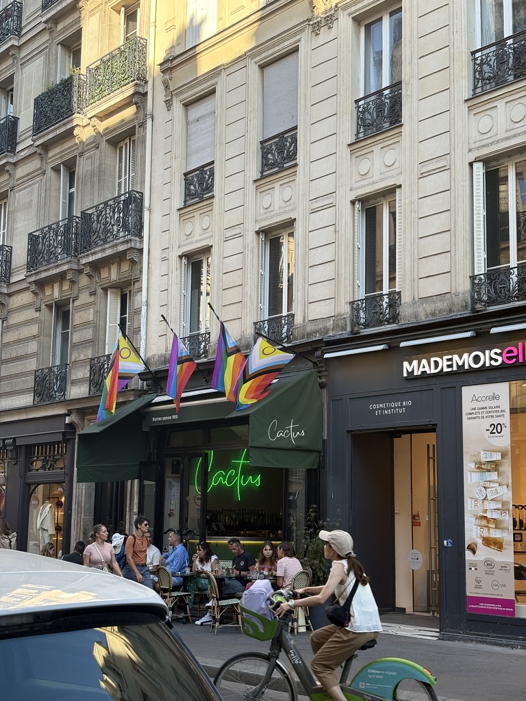 Photo of the Cactus Bar, with its glowing neon and Progress Pride flags overhead.