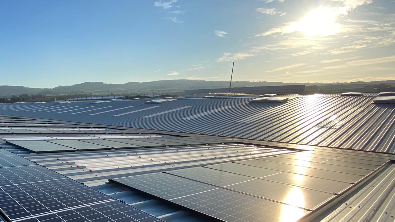 Solar panels installed on a metal roof at sunrise with hills in the background