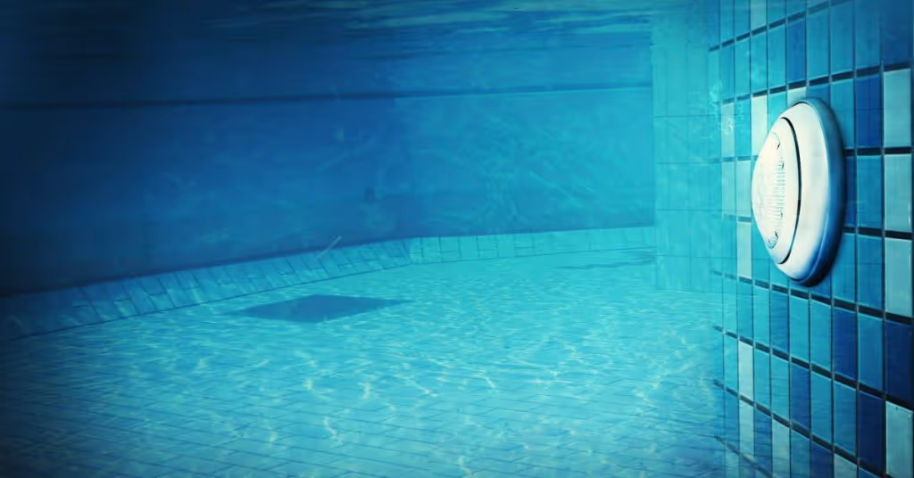 LED lights illuminating a pool’s interior. The lightbulbs are round and attached to the swimming pool’s tiling.