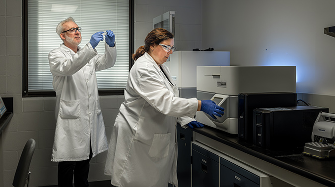 Two  scientists wearing lab coats working in a lab.