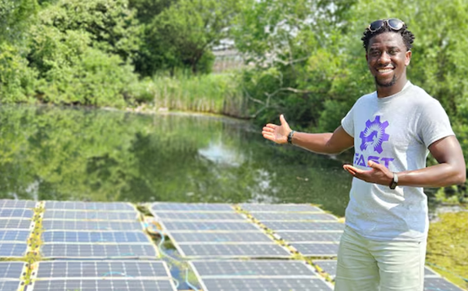 Man smiling and pointing to solar panels in a pond