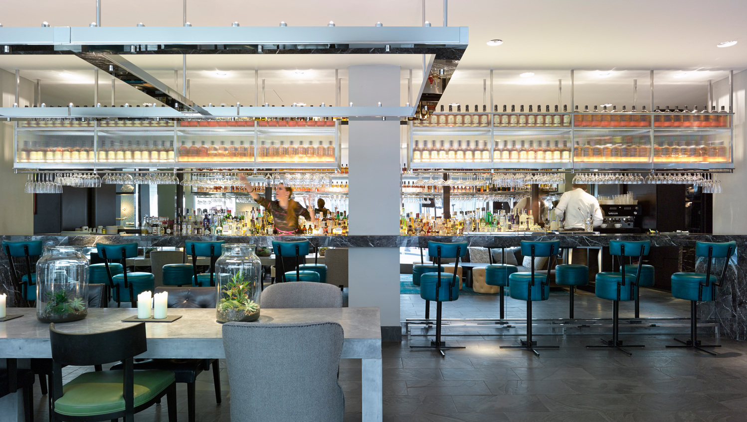 Restaurant and bar at South Place Hotel, with teal bar stools and a long back-lit bar