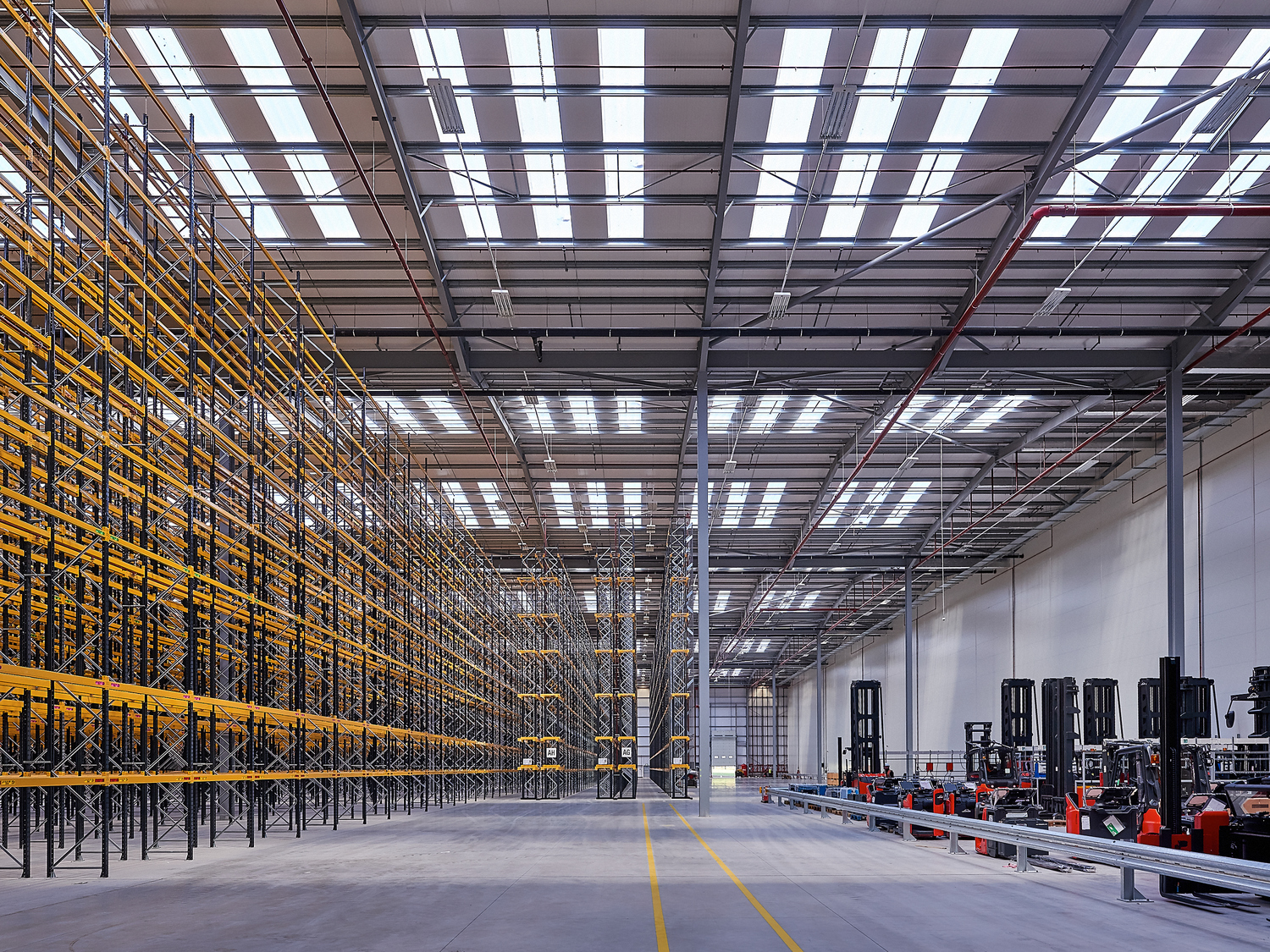 High-bay racking inside the Defence Fulfilment Centre, with forklift trucks parked along the aisle