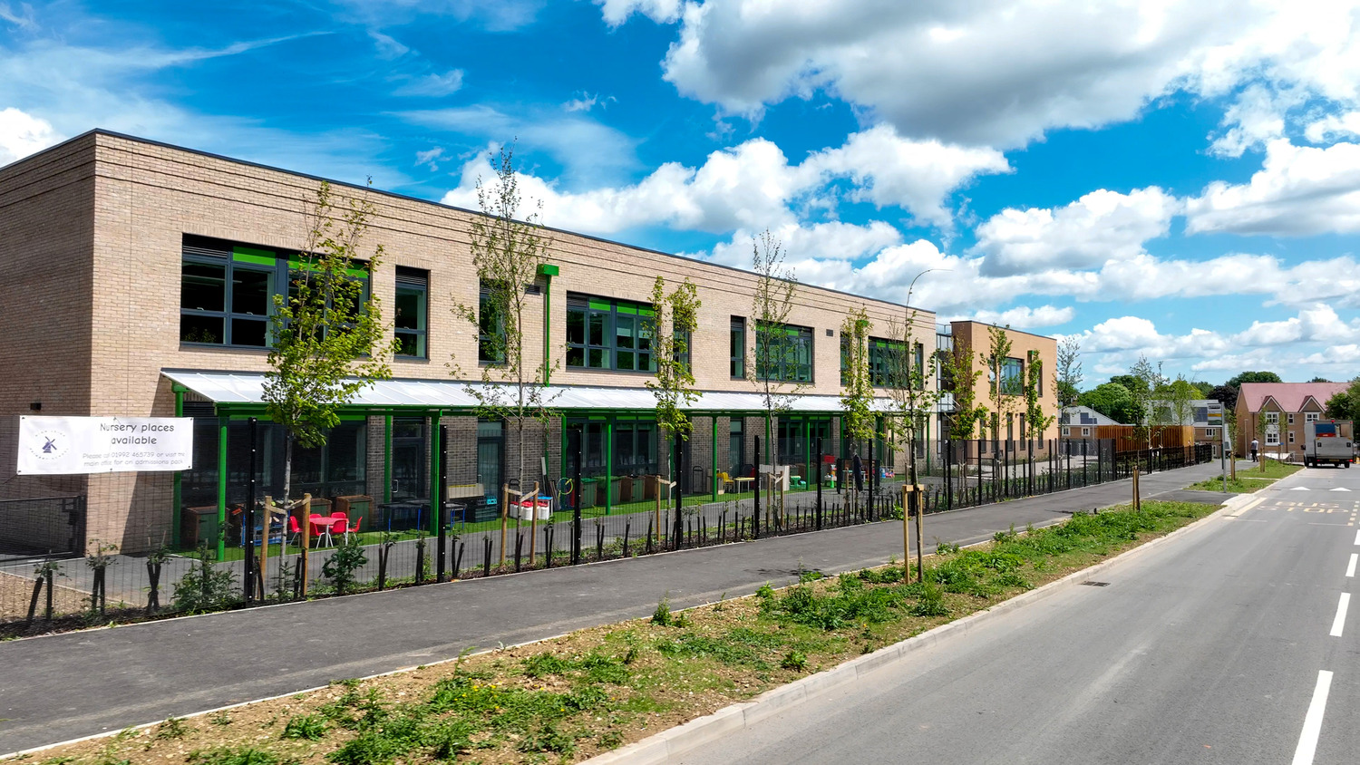High Leigh Primary School in Hoddesdon, a two-storey brick building with green window frames beside a new road