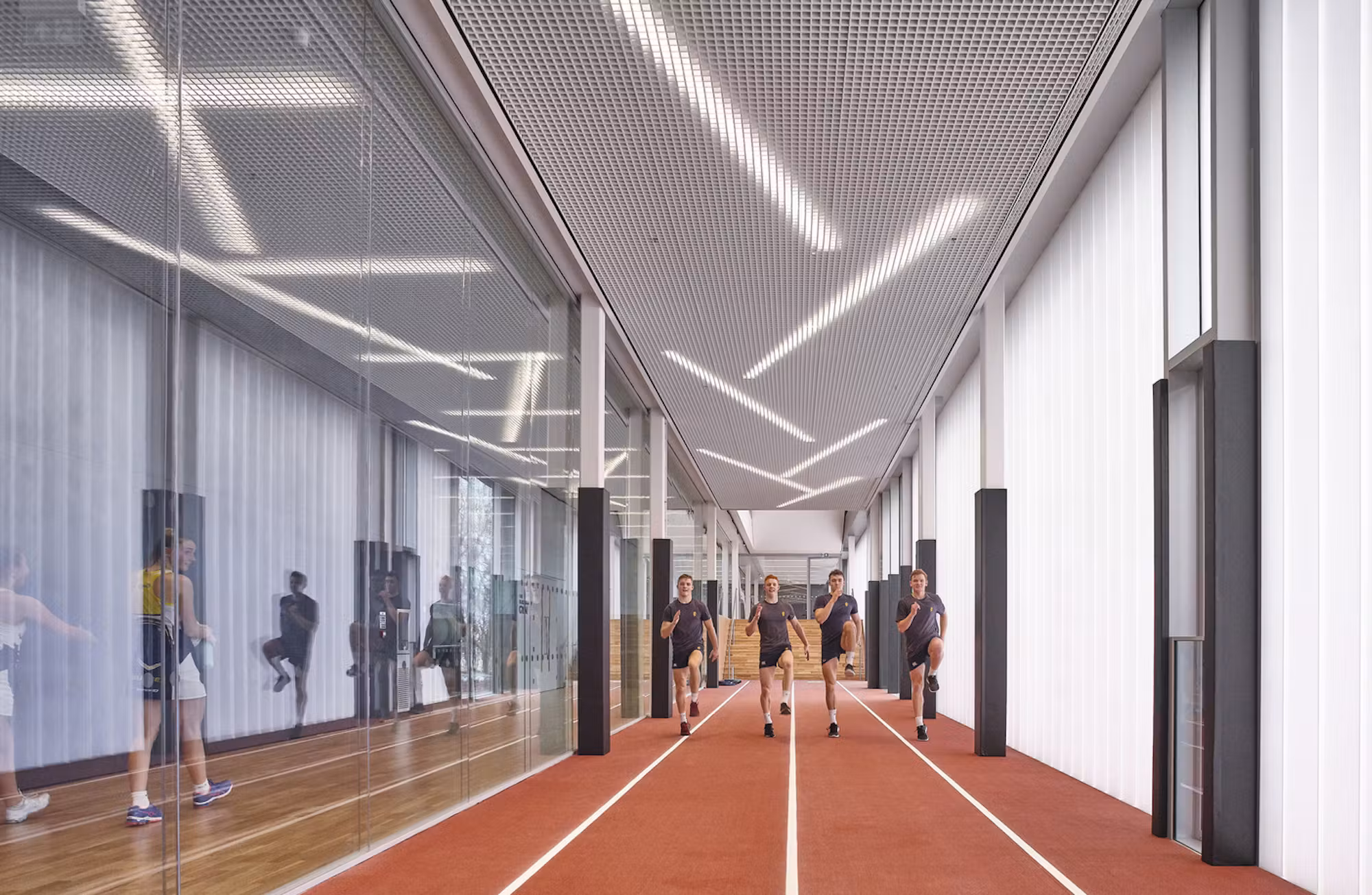 Indoor running track with glazed walls inside Brighton College Sport Science Building