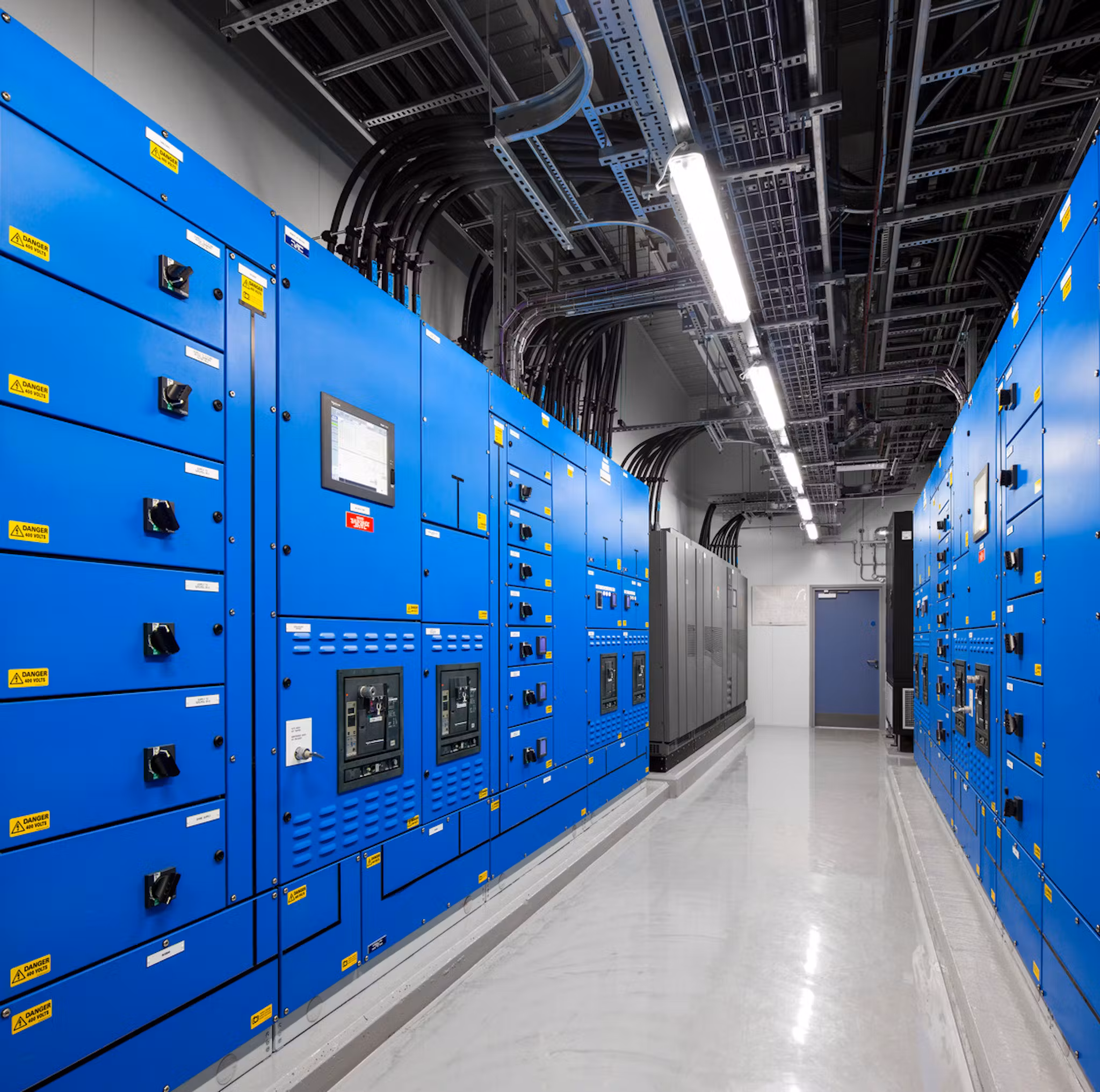 Corridor lined with blue electrical switchgear panels inside the Chessington data centre
