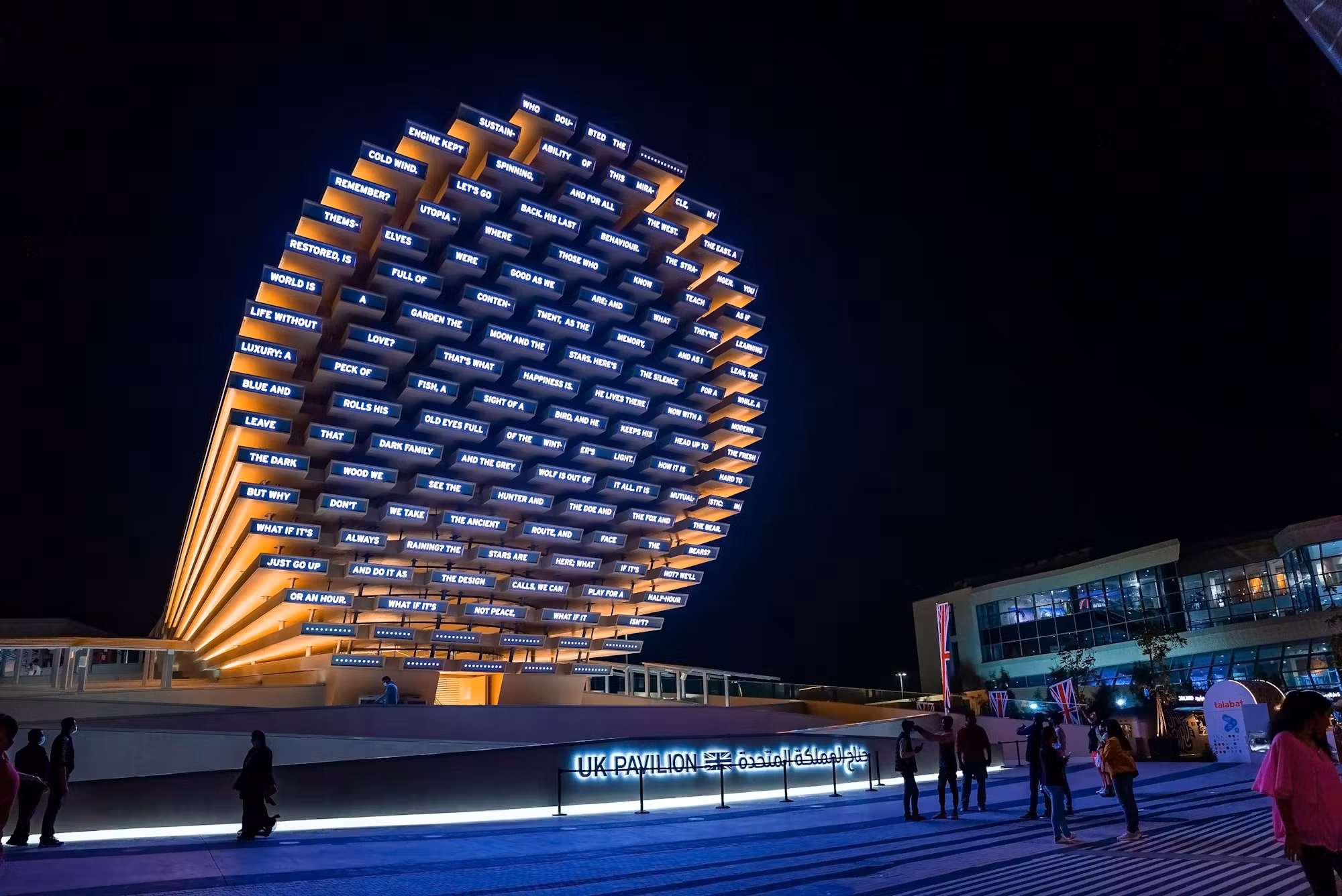 UK Pavilion at Expo 2020 Dubai lit up at night, its cone of timber slats displaying visitors' words