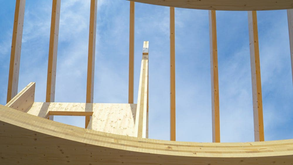 Timber structure of the UK Pavilion under construction against a blue sky