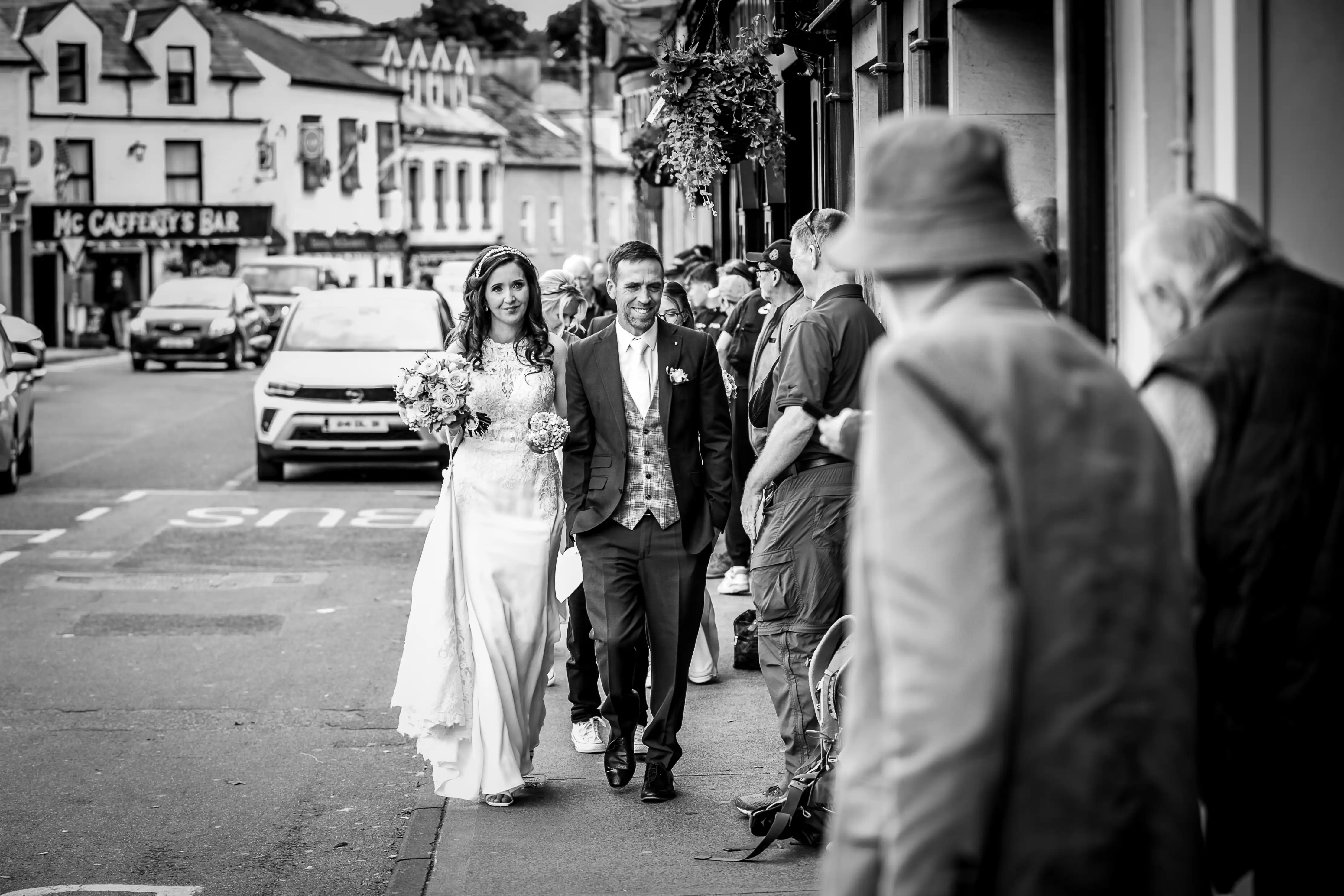 Newly married couple walking up a busy street