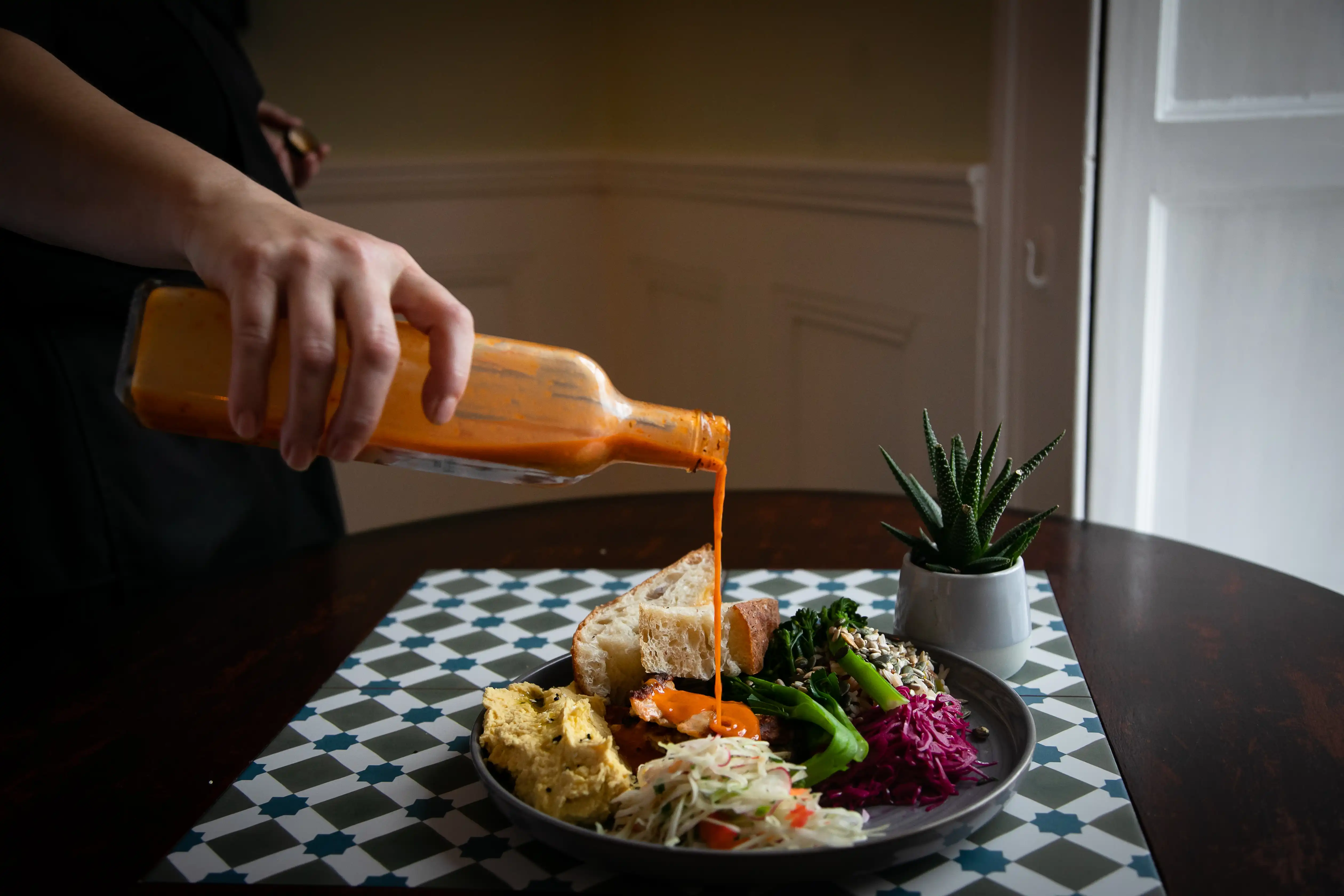 Chef pouring sauce on plate of food