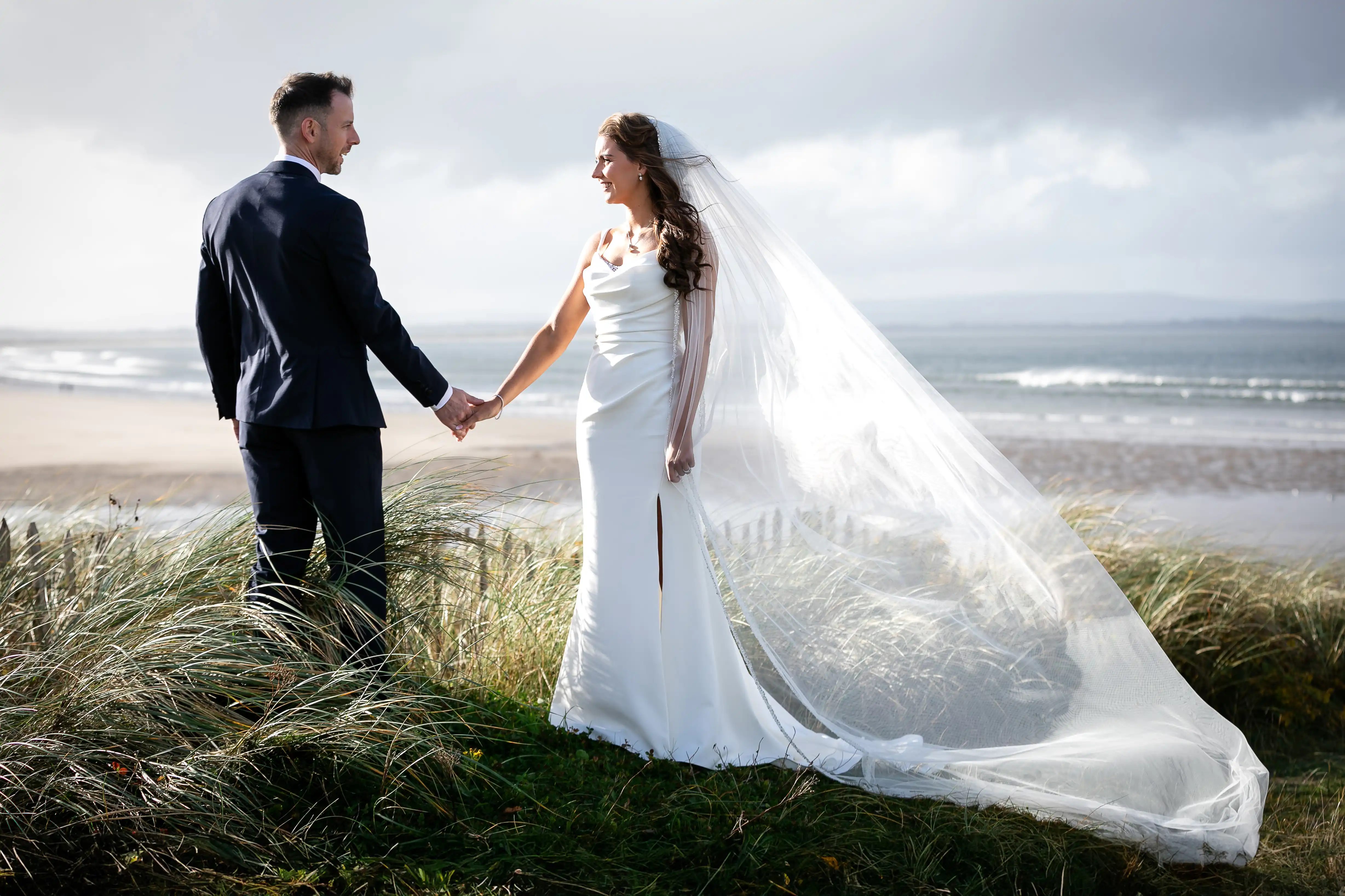 Bride and groom holding hands on beach