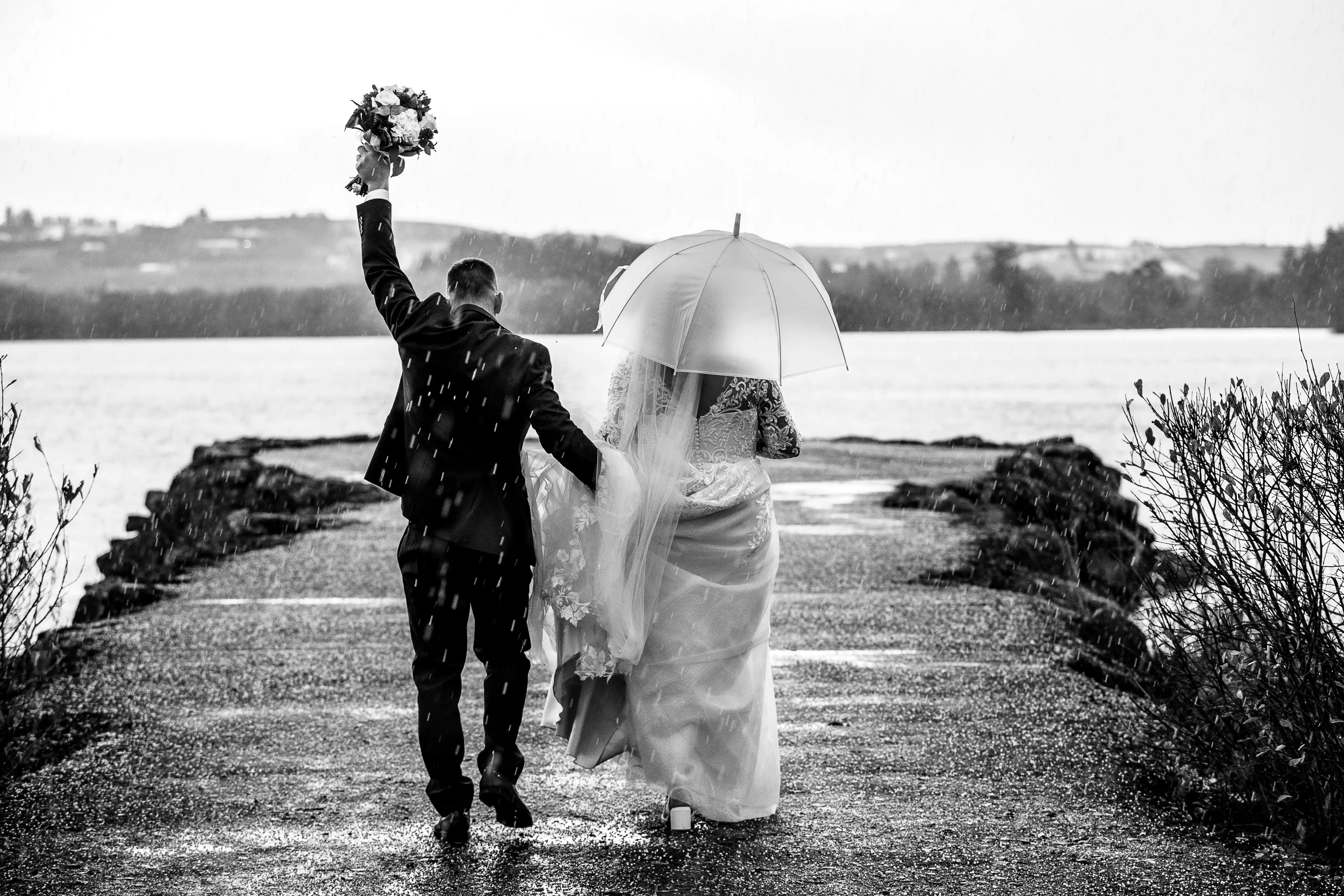 Groom waving flowers in the air while holding bride's hand