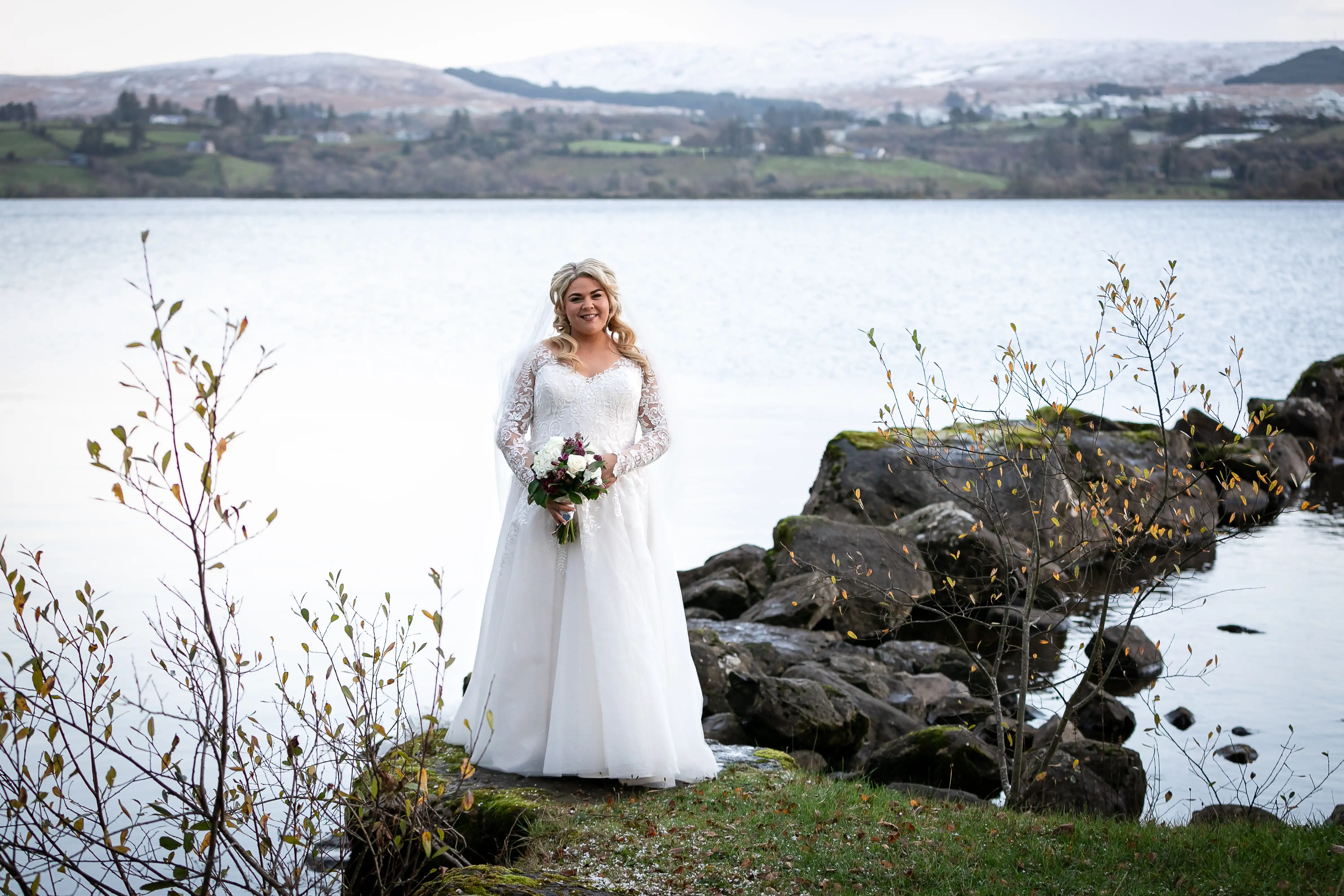 Bride holding flowers in front of lake