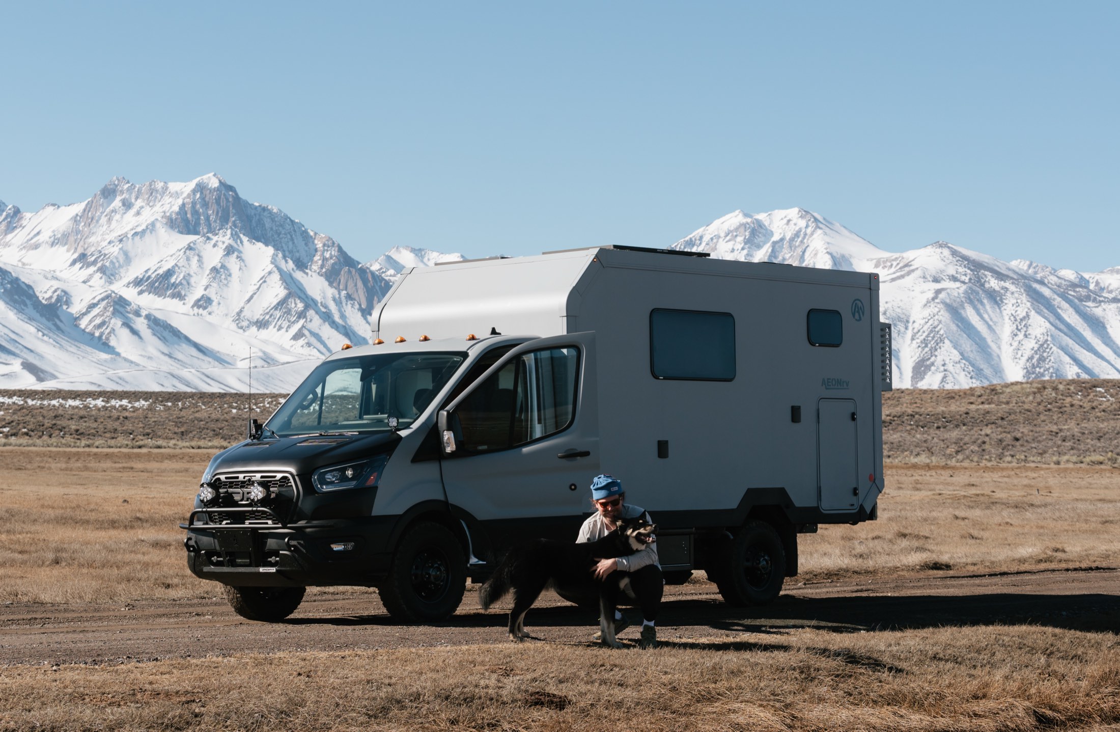 An owner and their dog with an AEONrv below the Sierra Nevada