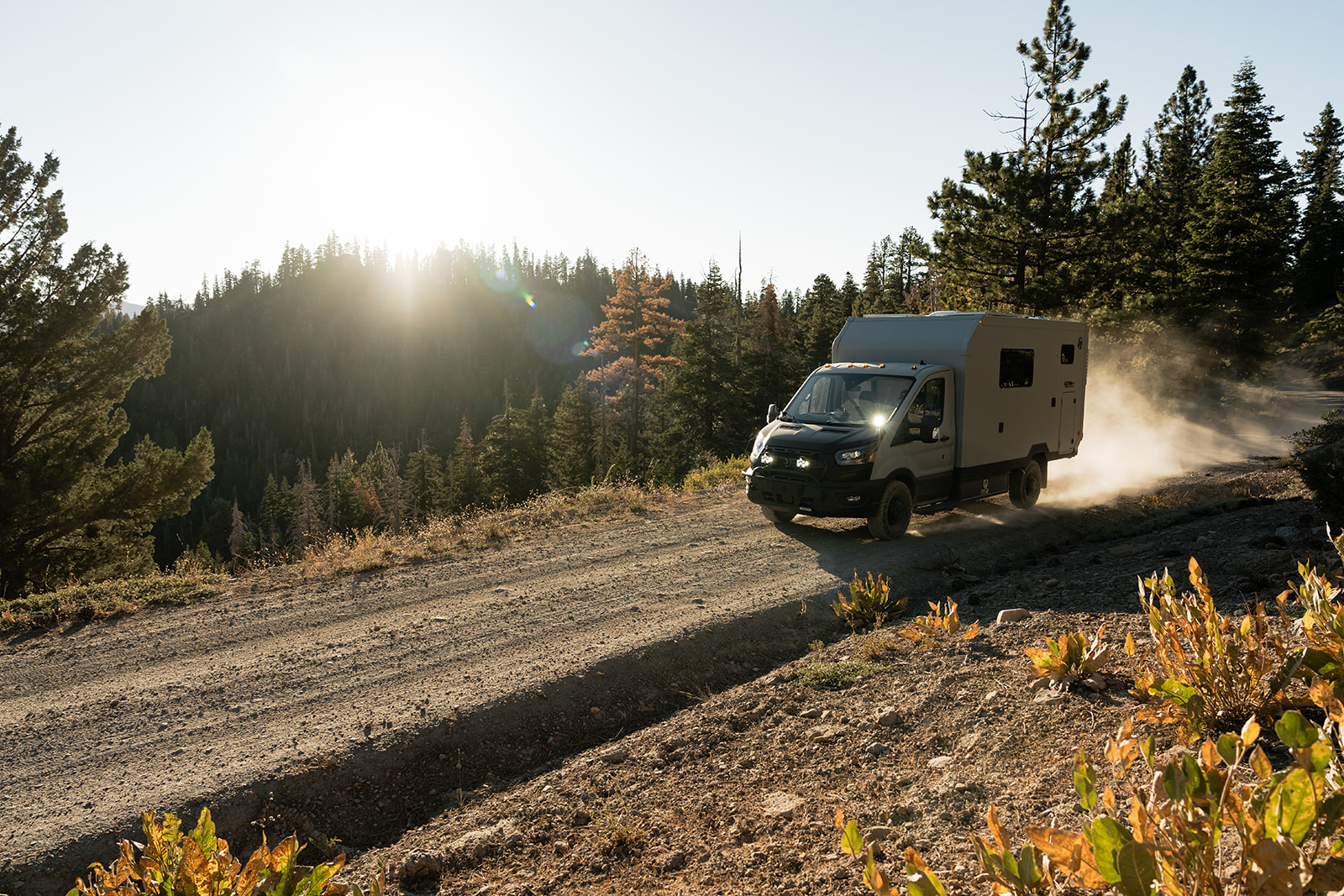 AEONrv on a dirt forest road at sunrise, dust behind the rear wheels