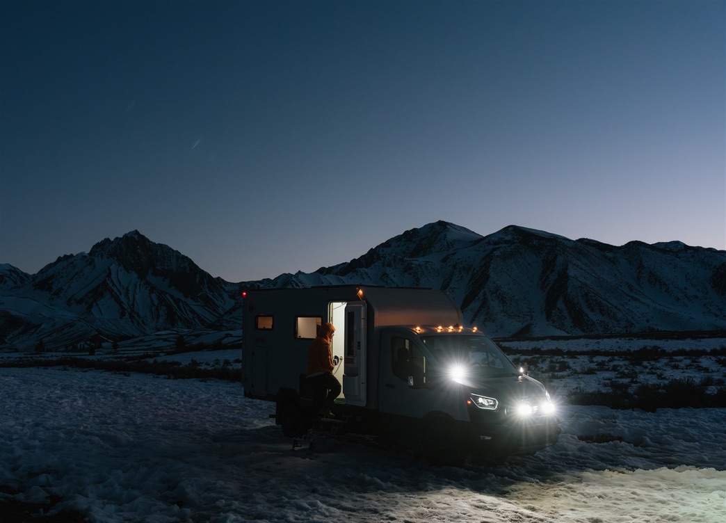 AEONrv at dusk in the snow, cabin lit from inside