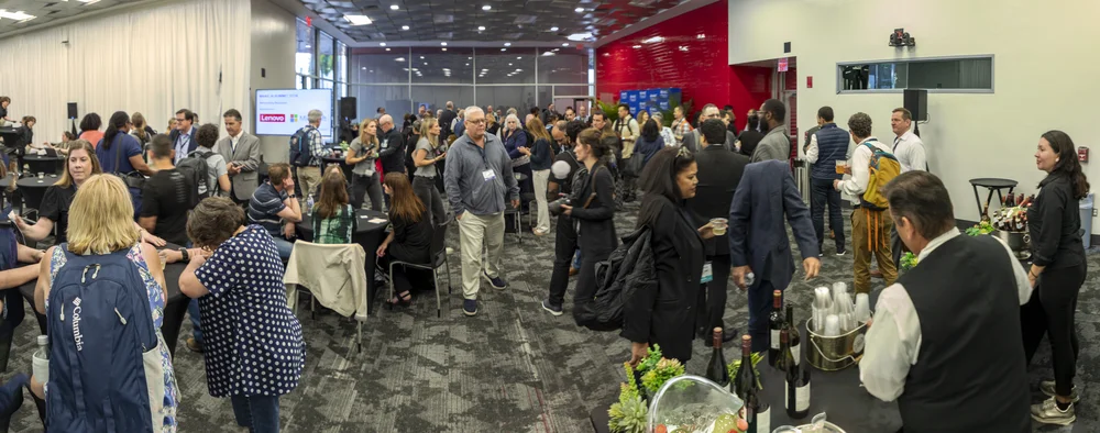Conference networking session with a diverse group of people conversing and mingling in a modern indoor space.