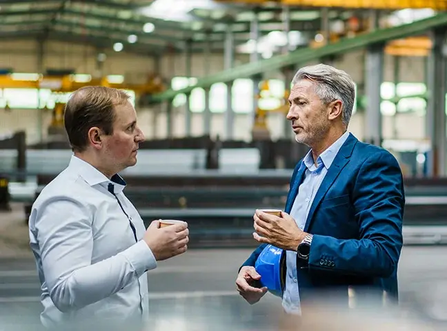 Mise en relation, deux dirigeants en discussion dans un entrepôt industriel.