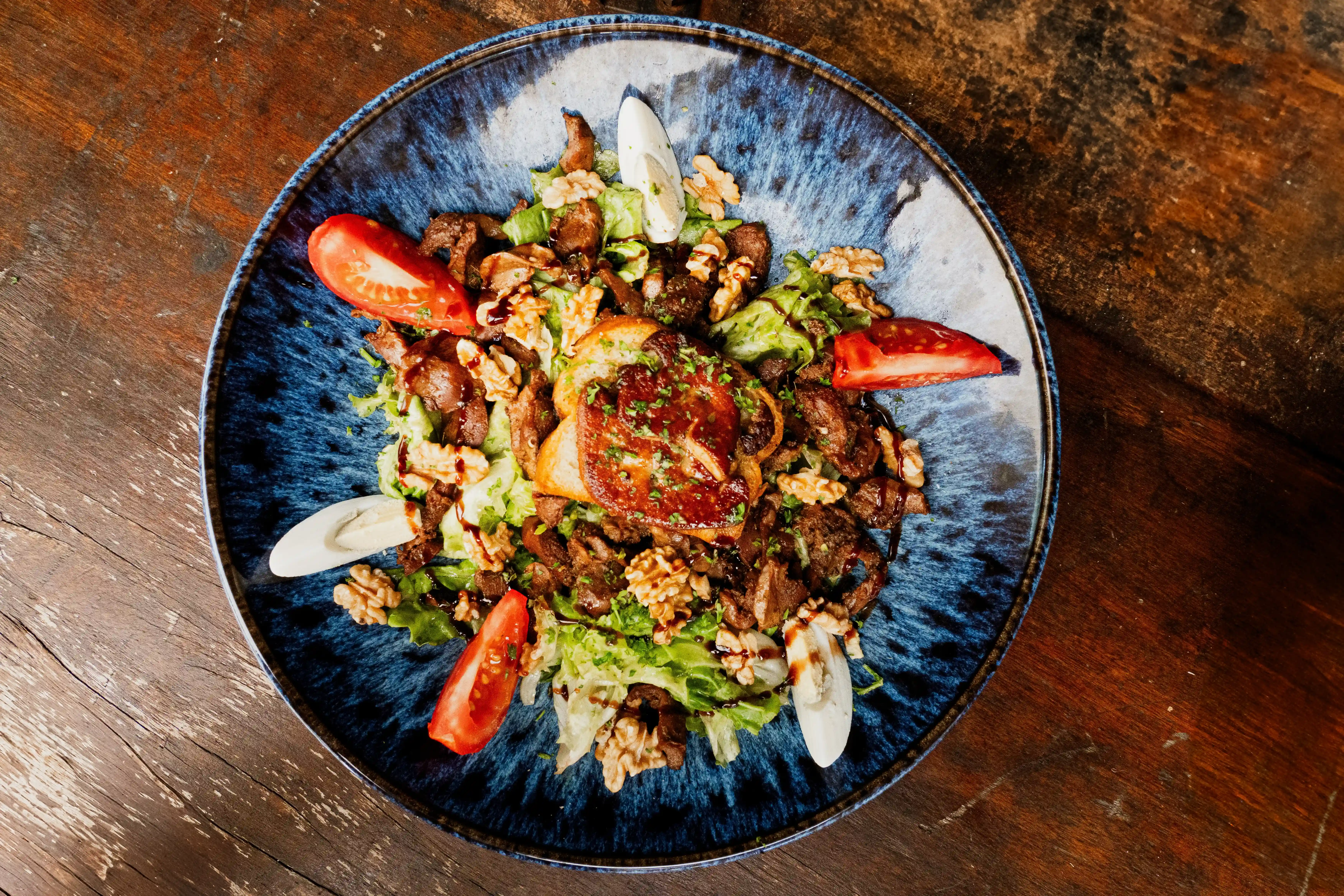 Salade Vigeoyeuse : gésiers, foie gras poêlé, condiments, spécialité locale de la brasserie Jibé